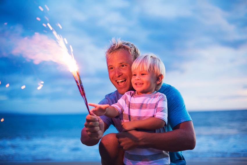 Man with son looking at a sparkler