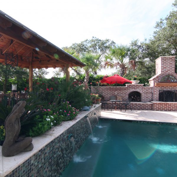 Backyard pool surrounded by brick oven and eating area