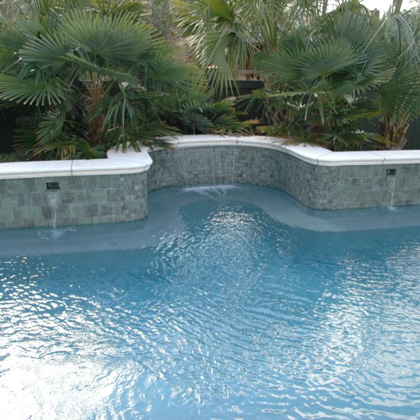 front view of outdoor pool with one large waterfall and four smaller ones