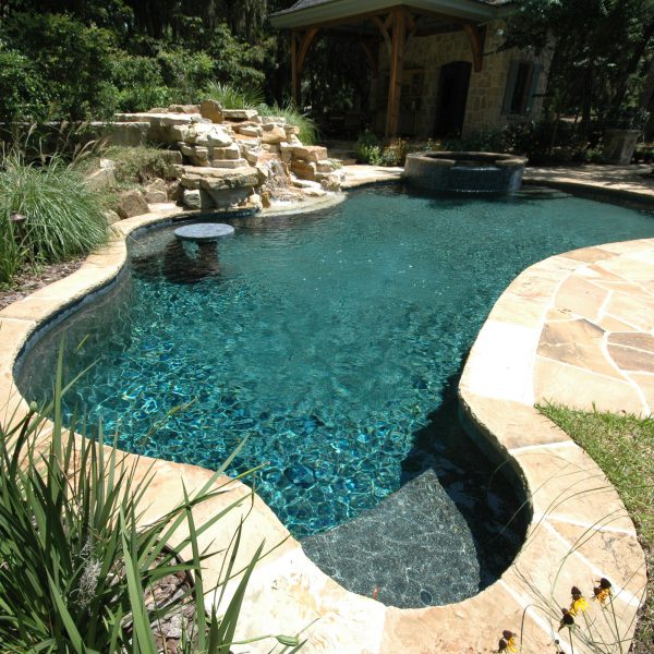 Outdoor pool with rock waterfall and circle hot tub