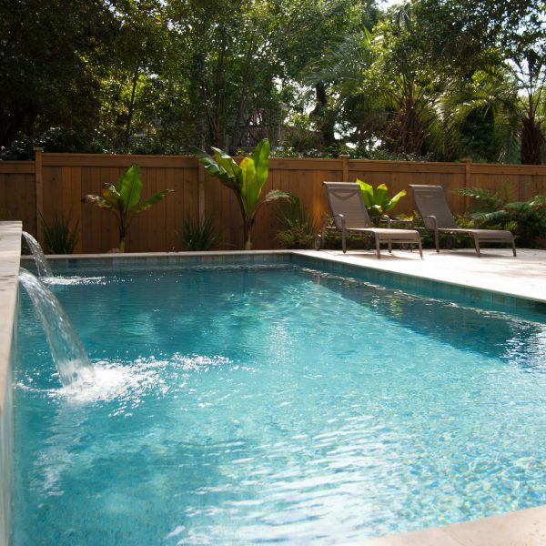 Outdoor pool with two water fountains and lounge chairs next to the pool