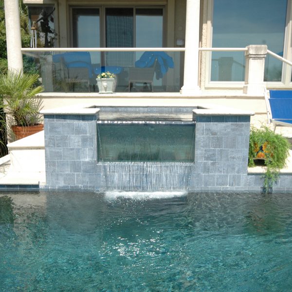 Front view of infinity pool, water fall feature and back of a beach house