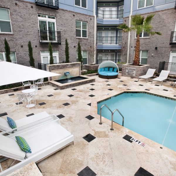 Outdoor pool in Elan Midtown apartments courtyard with palm tree and lounge chairs