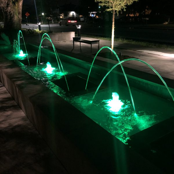 Outdoor water feature fountain at night with green lights