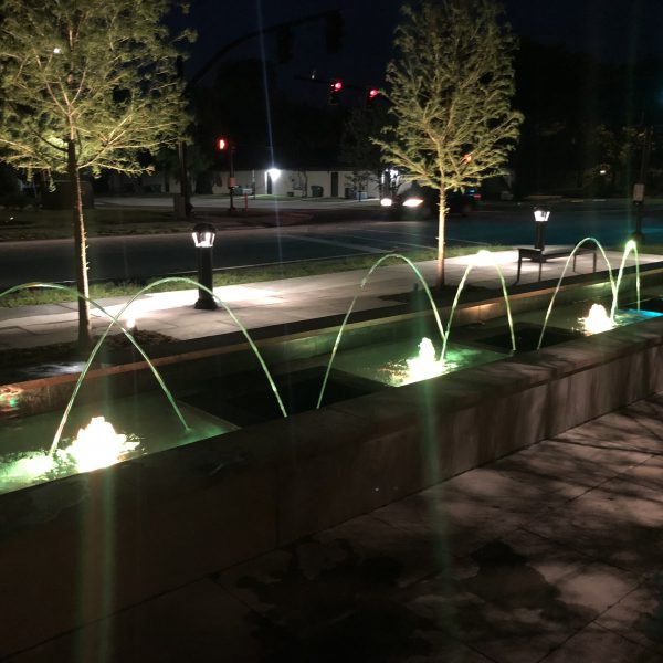 Outdoor water feature fountain at night with yellow lights