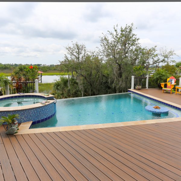 Family Infinity Pool with Custom Spa overlooking a backyard lake