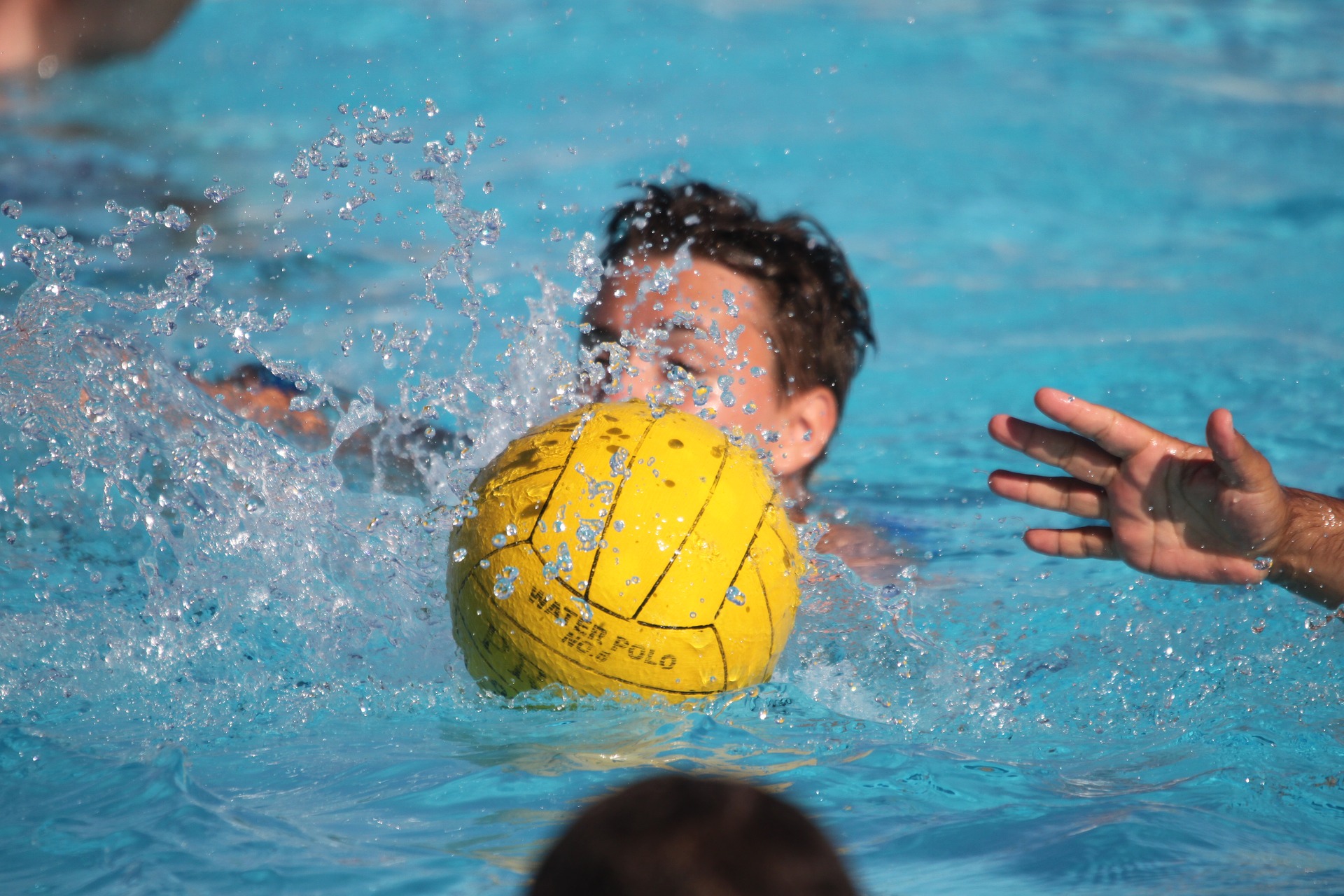 Boy playing with ball in pool