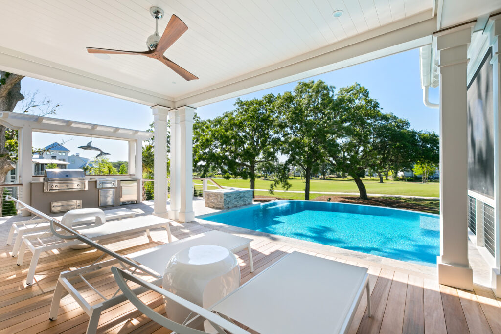 Porch with lounge chairs and grill area overlooking backyard pool