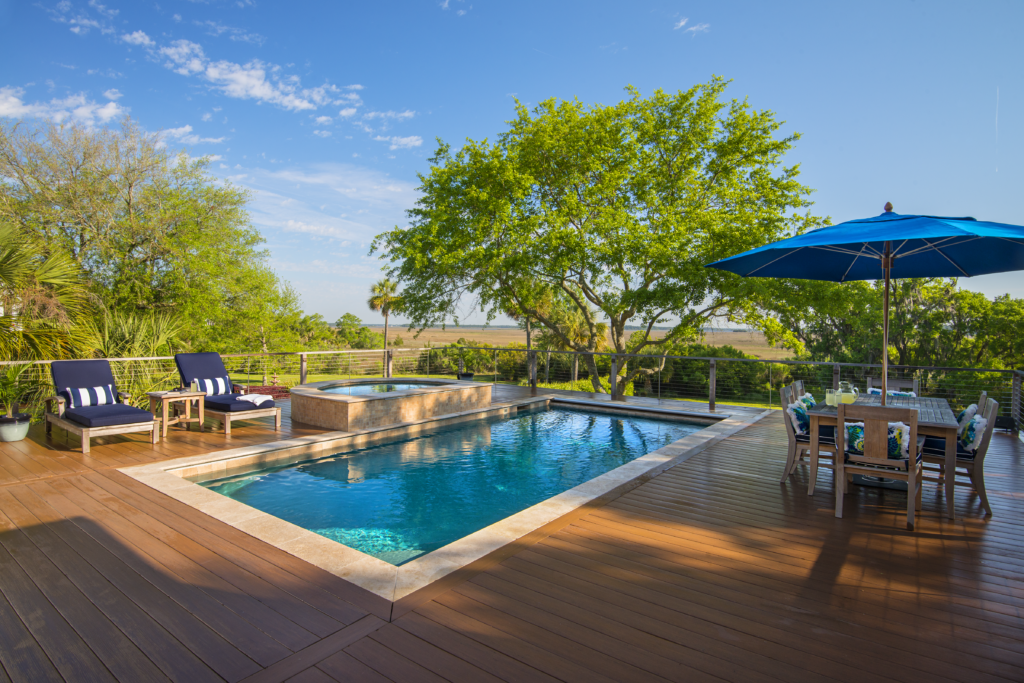 Backyard pool overlooking marsh with lounge chairs and table