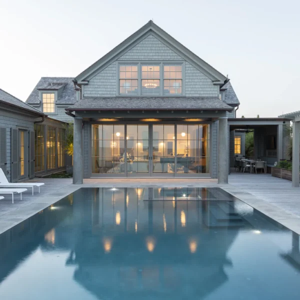 Sleek backyard pool reflecting a contemporary coastal home at twilight.