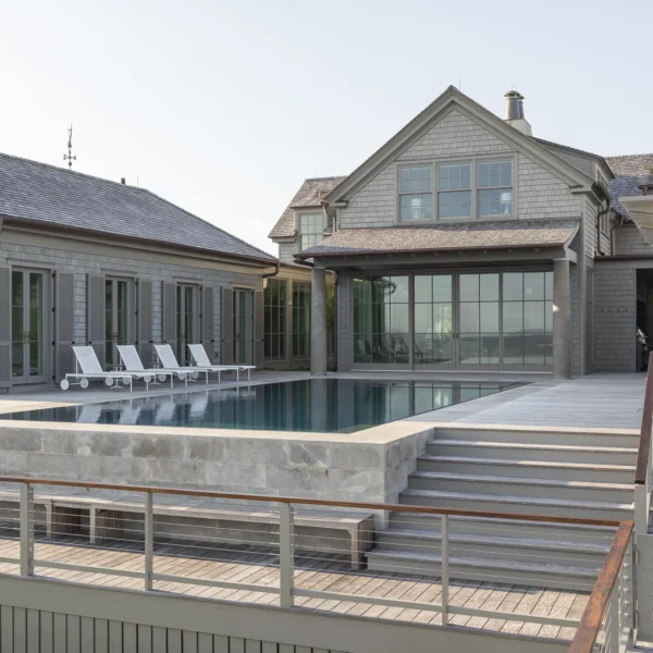 Multi-level deck with an infinity pool and a grand coastal residence.