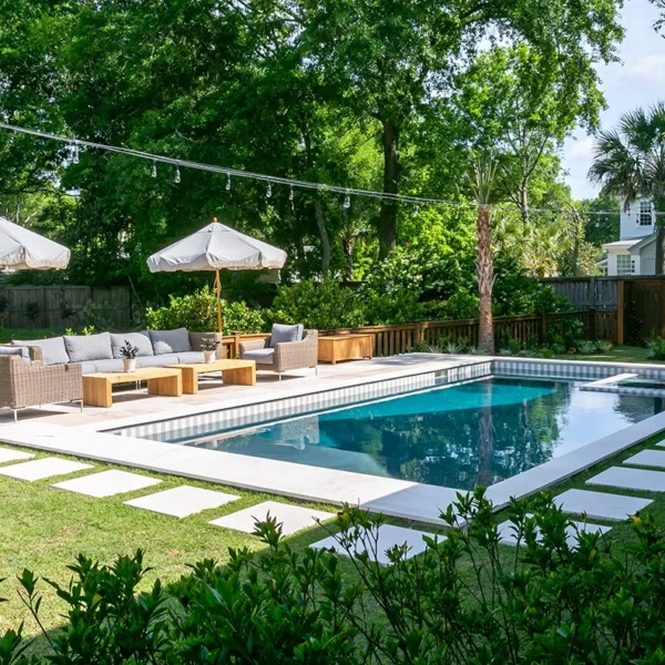 Inviting backyard pool area with cushioned seating, umbrellas, and string lights for ambiance.