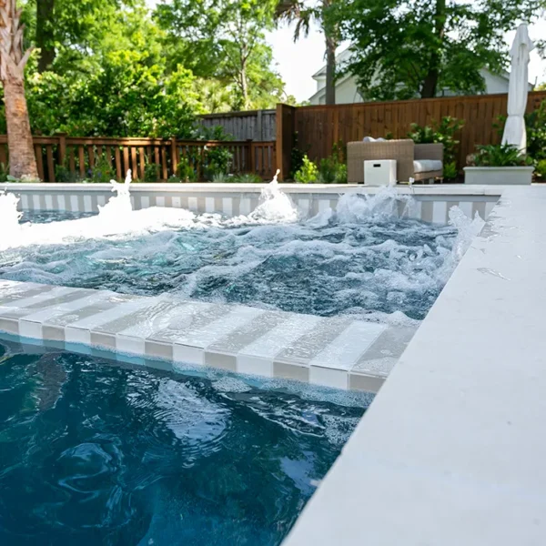 Close-up of a bubbling hot tub section with strong water jets in a stylish in-ground pool.