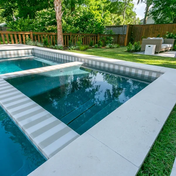 Close-up view of a modern integrated spa connected to a rectangular backyard pool with striped tile design.