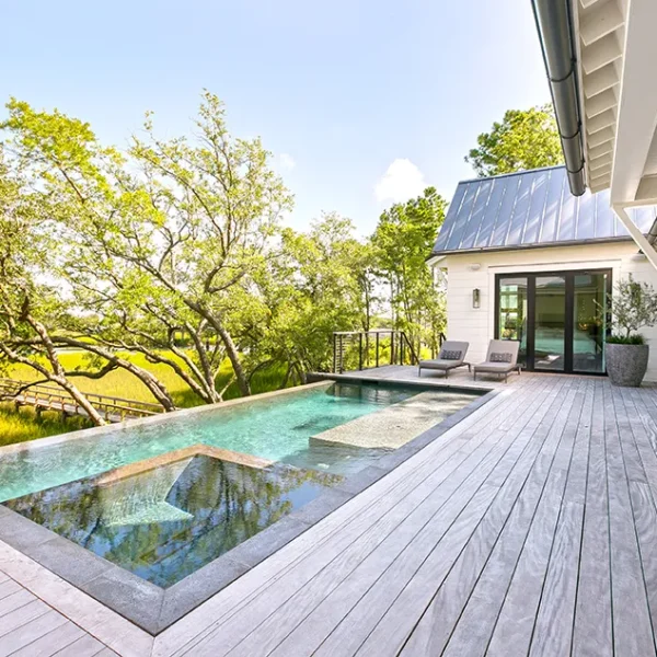 Contemporary marshfront pool with tanning ledge and wood deck