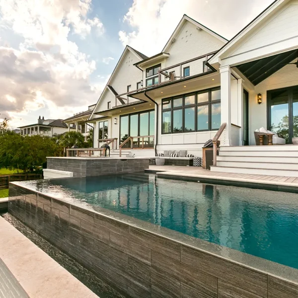Elevated luxury infinity pool with spillover design and modern home exterior