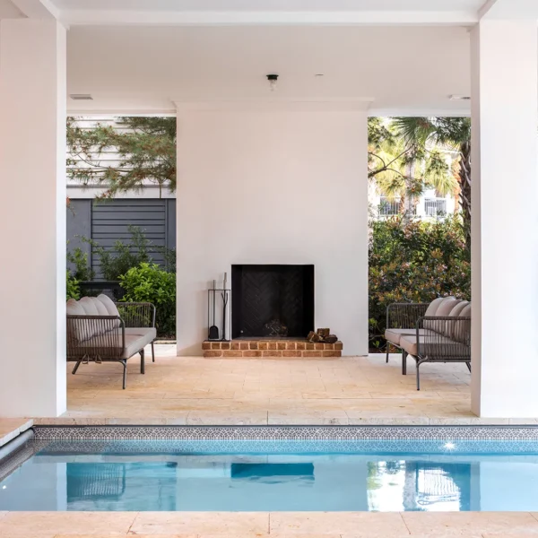 Covered outdoor pool and patio with fireplace and lounge chairs.