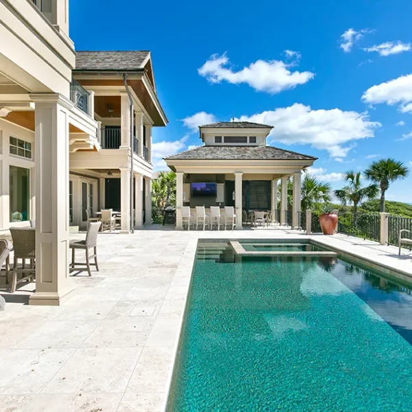Elegant oceanfront property featuring a lap pool and open-air dining area with coastal views.