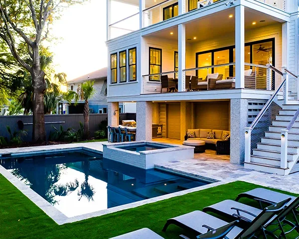 Upscale pool area with lounge seating and outdoor kitchen attached to a luxury home.