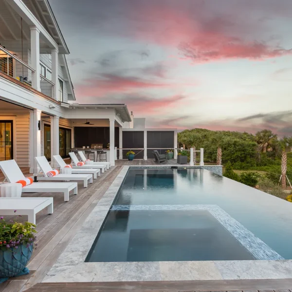 Infinity edge pool with modern lounge chairs and ocean views at sunset