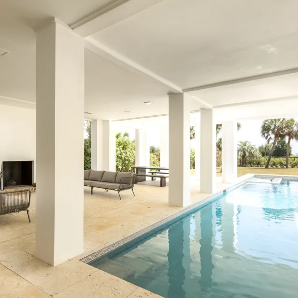 Covered patio with indoor-outdoor pool, fireplace, and modern furniture.