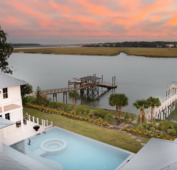 Infinity pool overlooking marsh and private dock at sunset