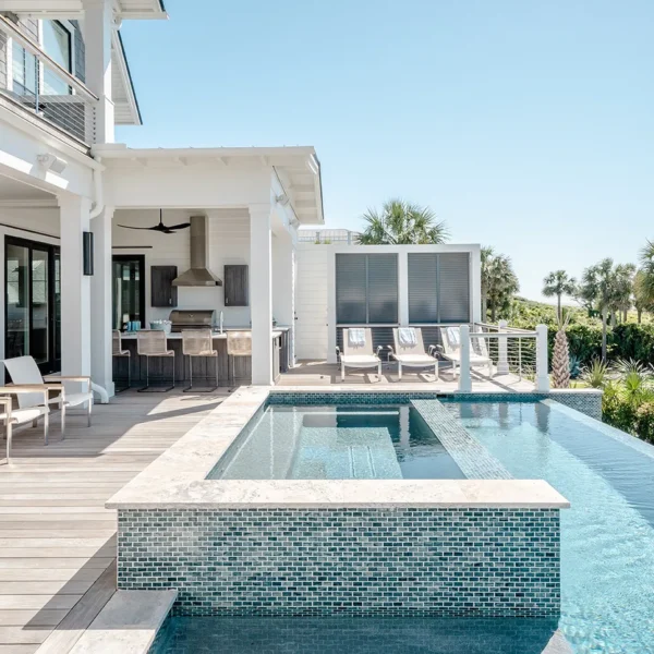 Infinity-edge pool with elevated spa and outdoor kitchen beside a luxury beachside residence