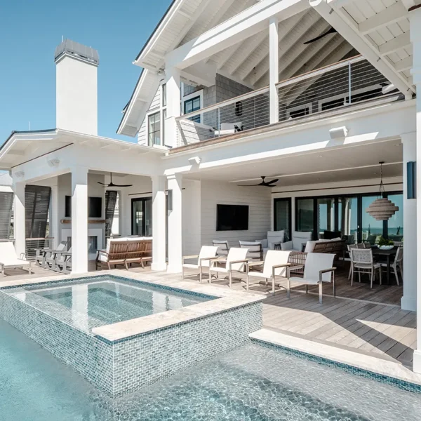 Luxury coastal pool with mosaic-tiled spa surrounded by shaded seating and dining spaces
