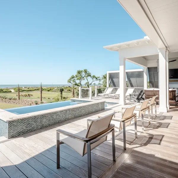 Oceanview infinity pool and spa with modern lounge chairs on wooden deck
