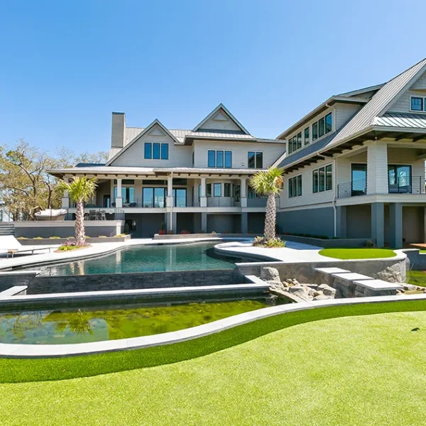 Expansive coastal home with tiered pool design, including an infinity pool, spa, and koi pond near a putting green.