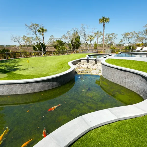 Winding koi pond and waterfall feature integrated into a green putting green landscape.