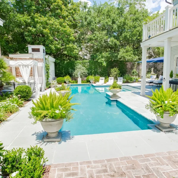 Beautiful backyard pool surrounded by green plants and outdoor seating areas.