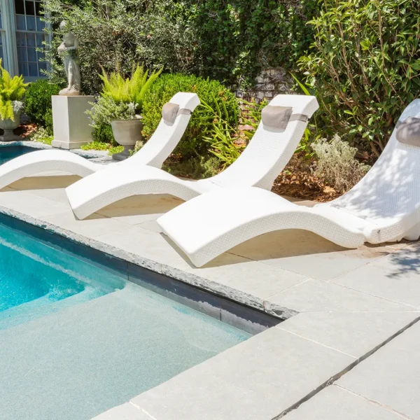 In-pool lounge chairs on the edge of a modern swimming pool.