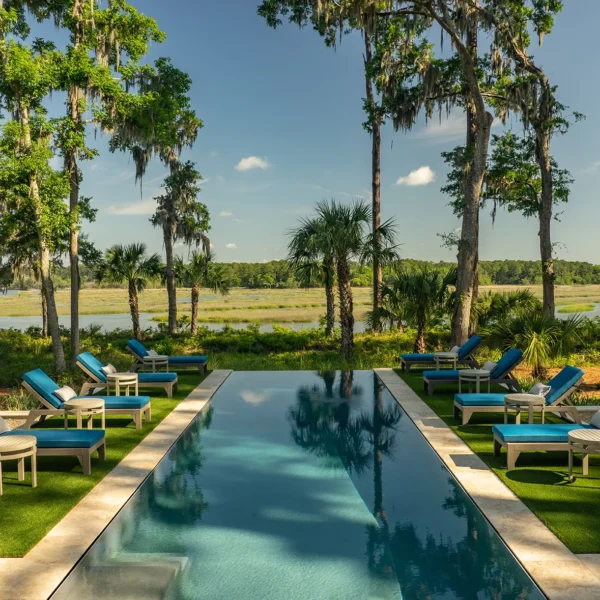 Expansive beachfront pool deck overlooking the ocean with shaded lounging area and modern furniture