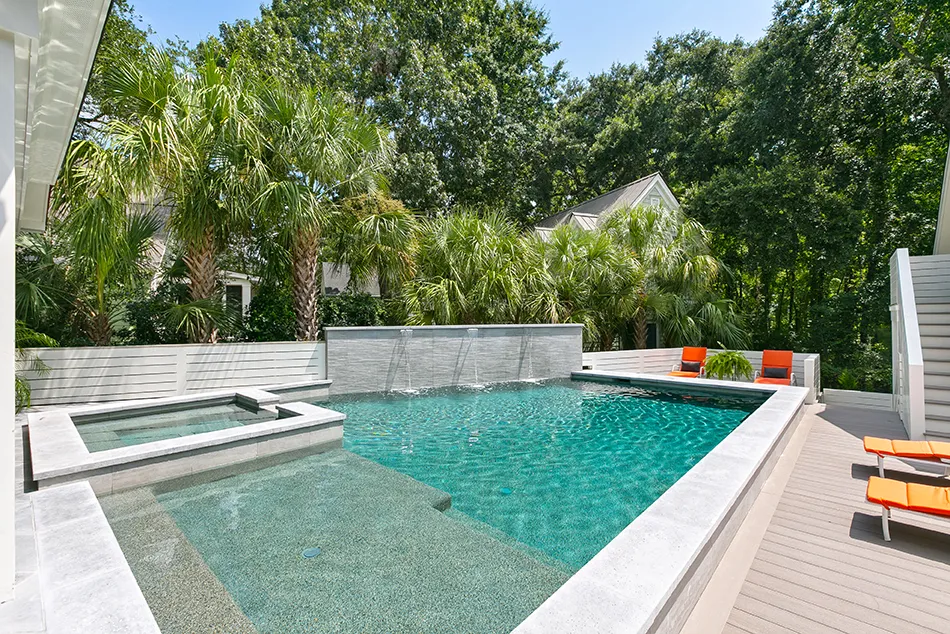 Contemporary backyard pool and spa with waterfalls and tropical landscaping.