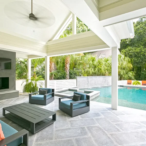 Luxurious outdoor living space with a fireplace, TV, comfortable seating, and a view of the pool and spa.