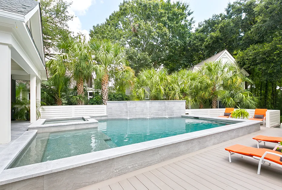 Backyard swimming pool with a spa, waterfalls, and orange lounge chairs.