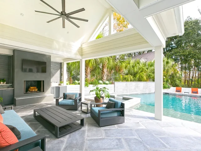 Covered patio with a fireplace, TV, outdoor kitchen, and a view of the pool and spa.