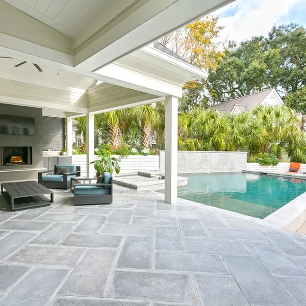 Spacious outdoor patio with a fireplace, comfortable furniture, and a view of the backyard pool and spa.