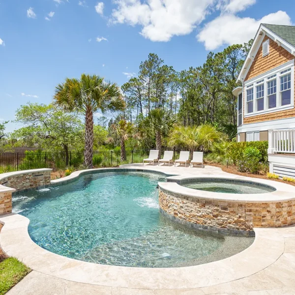 Resort-style backyard pool with spa, waterfalls, and tropical landscaping.