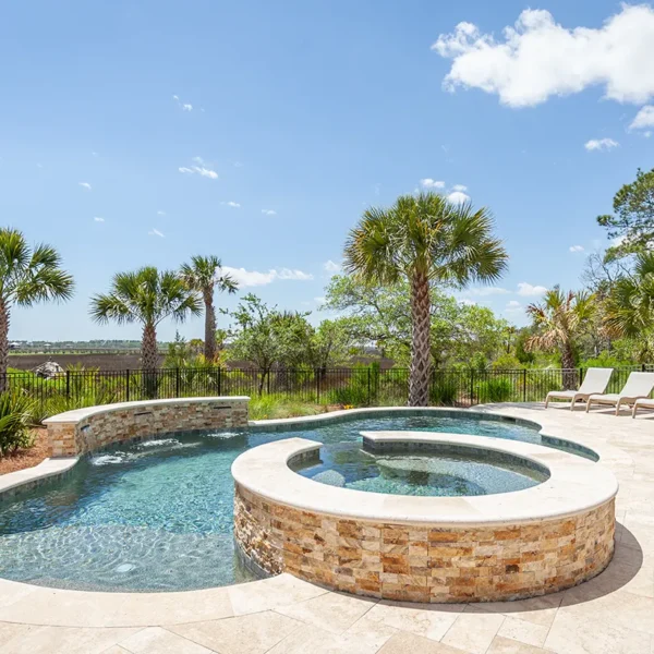 Lagoon-style pool and spa with tanning ledges and palm trees.
